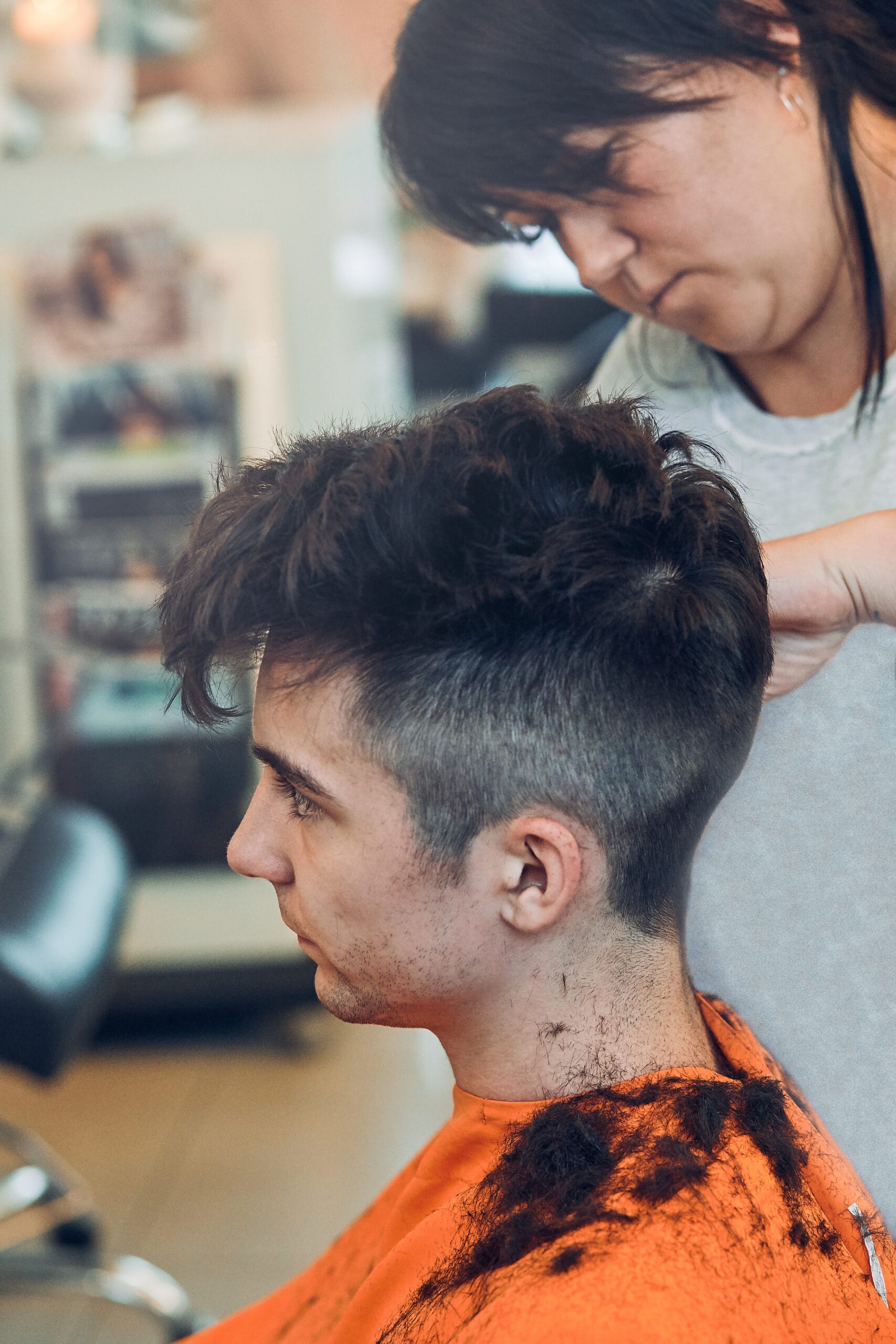 Hairdresser is haircutting styling young mans hair