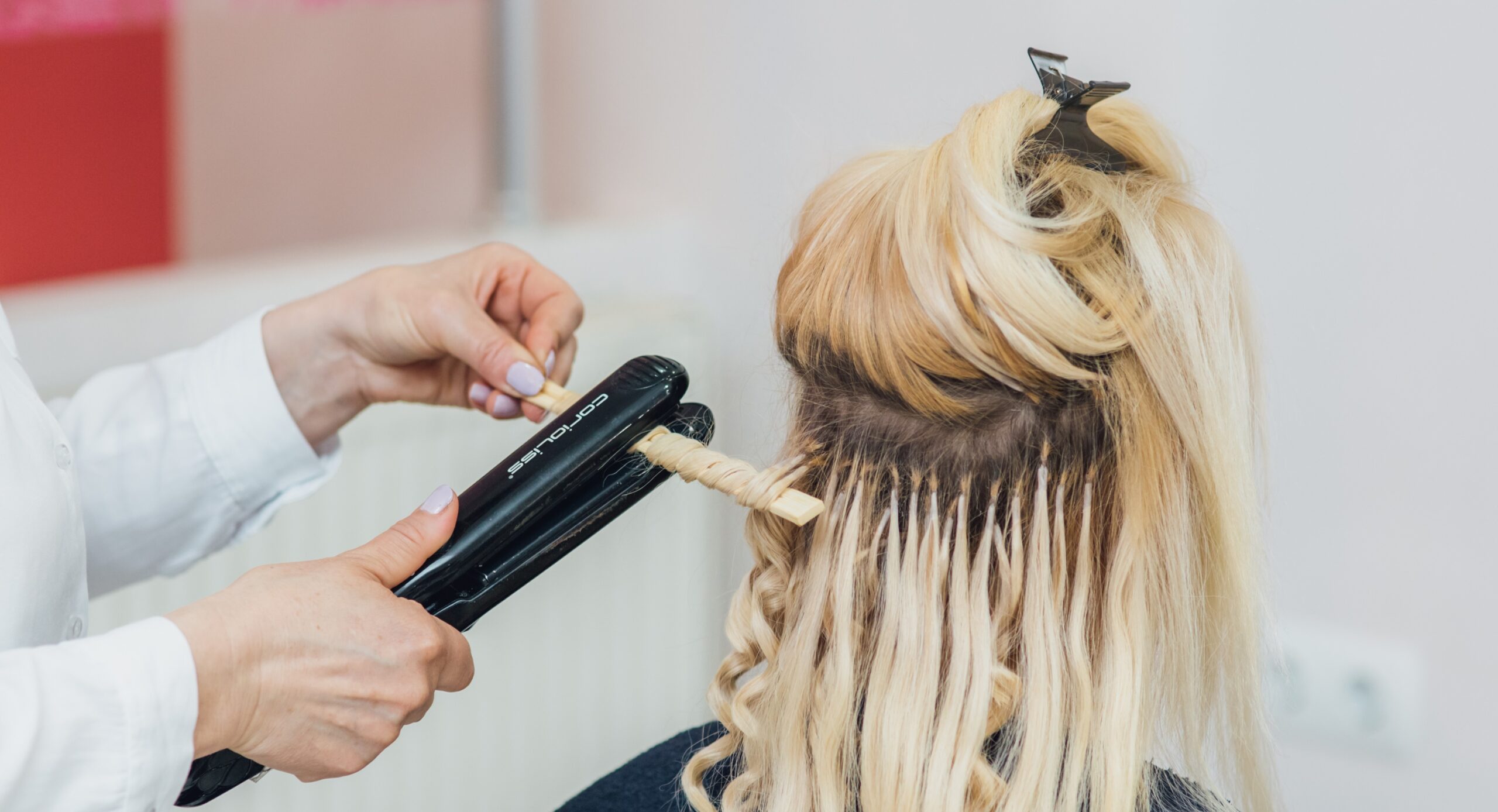 Hairdresser makes hairstyle close-up on blond hair of beautiful woman